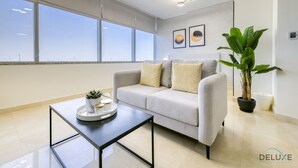 Una sala moderna con un sofá gris, una mesa de centro y una planta grande en maceta.