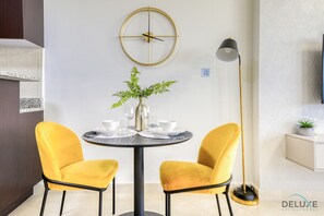 A modern dining area with a round table, two yellow chairs, a vase with green foliage, and a floor lamp.