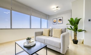 A modern living room with a grey sofa, a coffee table, and a large potted plant.