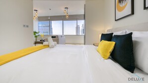 Habitación de hotel moderna con una cama grande, un escritorio, una silla y una ventana con vista a la ciudad.