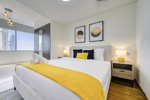 A modern hotel room with a large bed, a bedside table with a lamp, and artwork on the wall.