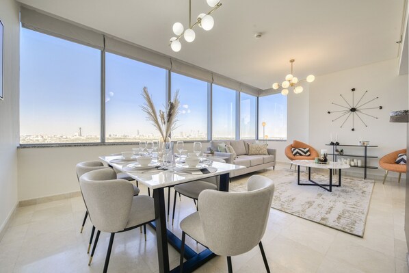 A modern dining area with a large table set for six, a sofa, two armchairs, and a coffee table.