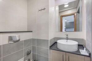 A modern bathroom with a round sink, a mirror, and a towel rack.