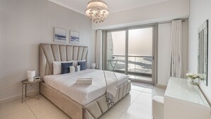 A modern bedroom with a large bed, a bedside table with a lamp, and a view of the city through large windows. - Scenic 1BR at Ocean Heights Dubai Marina by Deluxe Holiday Homes (Dubai)