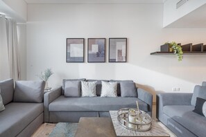 A modern living room with a grey sofa set, a coffee table with a tray, and framed abstract art on the wall.
