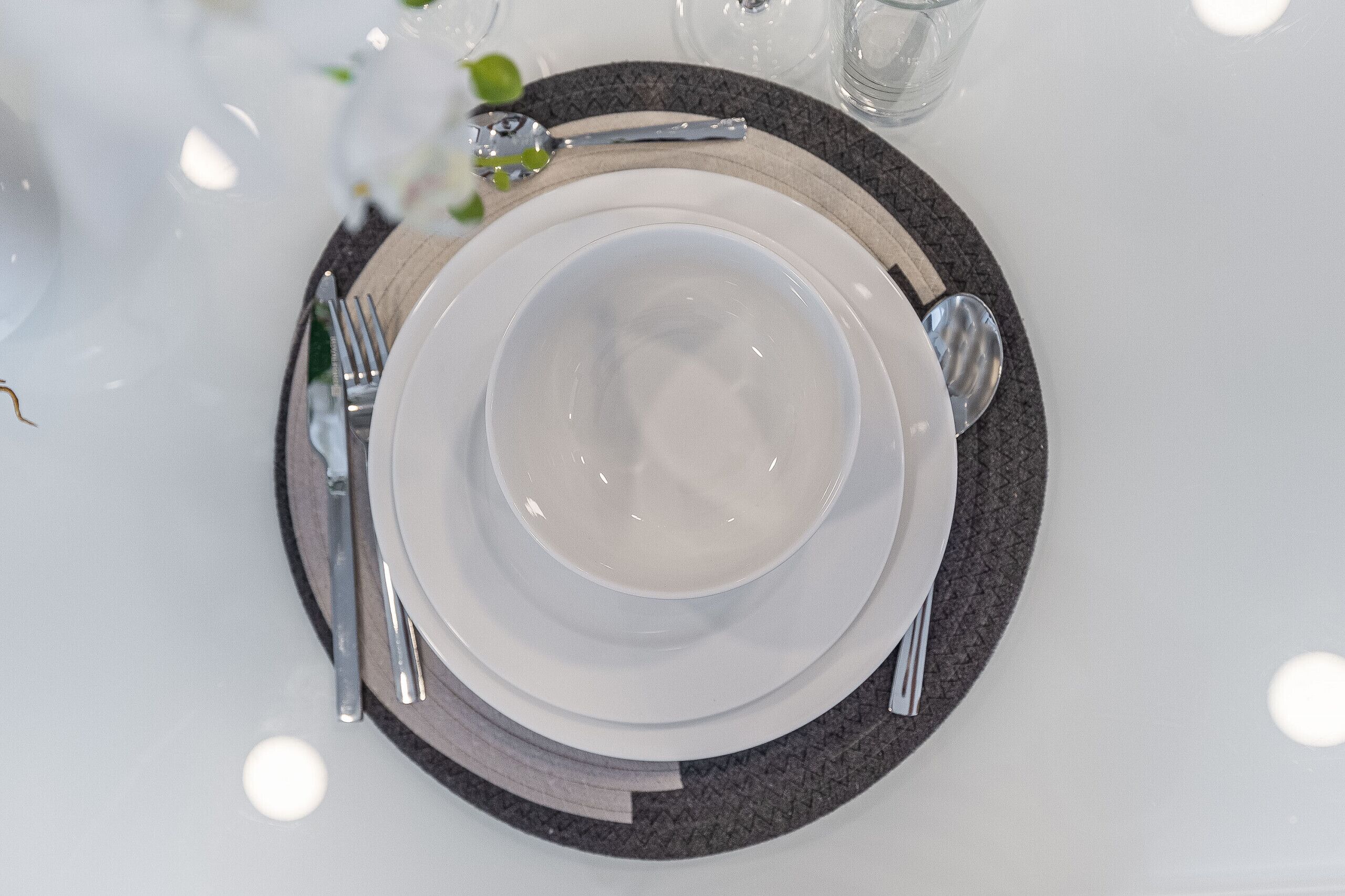 A neatly set dining table with a white plate, silverware, and a glass.
