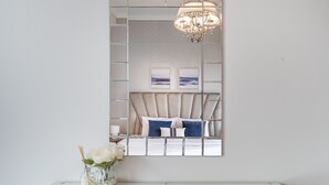 A modern bedroom with a glass partition, a chandelier, and a bed with blue and white bedding. - Scenic 1BR at Ocean Heights Dubai Marina by Deluxe Holiday Homes (Dubai)
