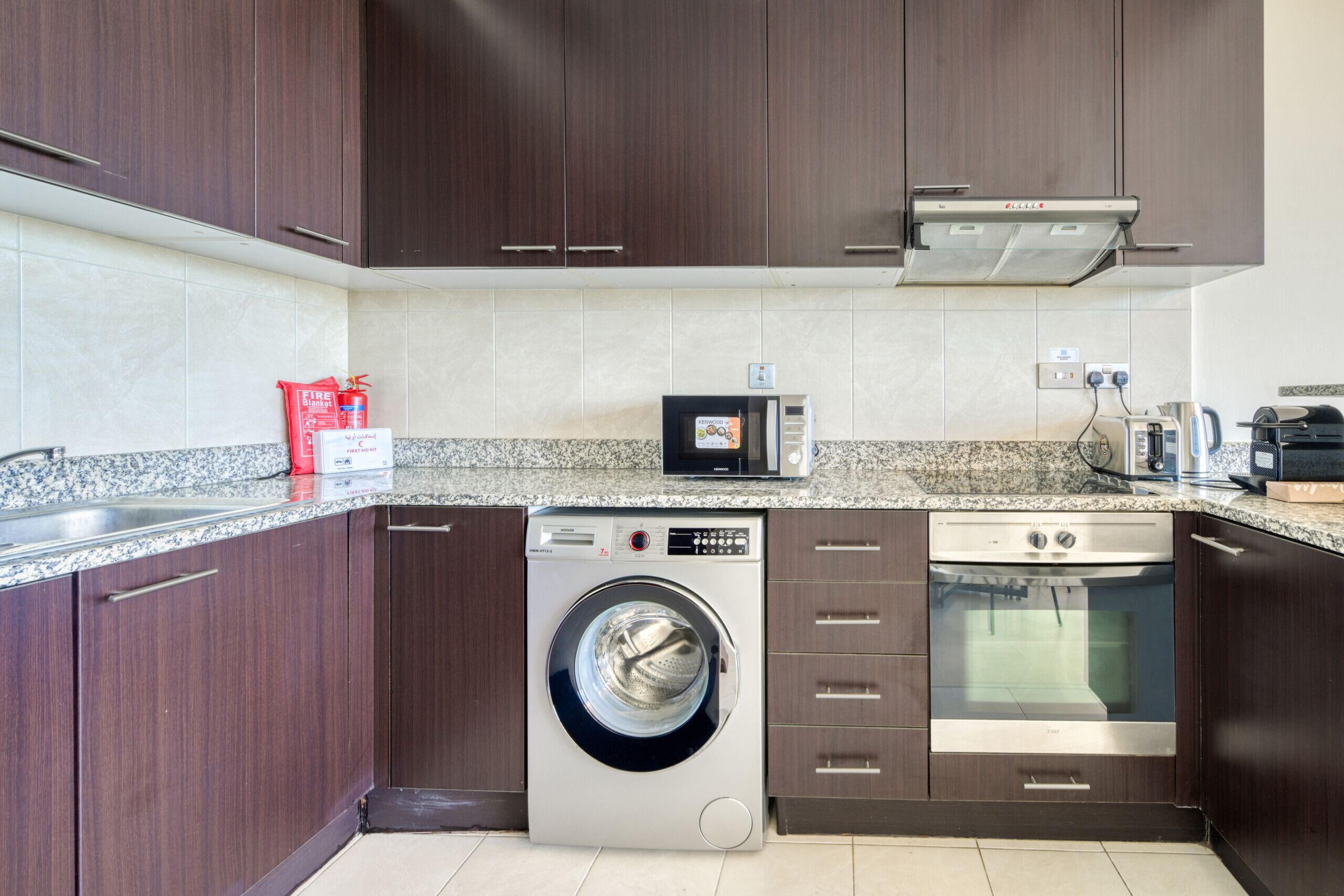 Cuina compacta amb rentadora, rentavaixelles, microones i forn.