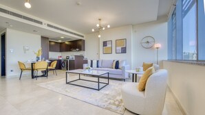 Uma sala de estar moderna com sofá, poltrona, mesa de centro e área de jantar.
