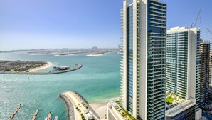 Un hotel de gran altura con vistas a la costa, incluyendo una playa y un puerto deportivo.