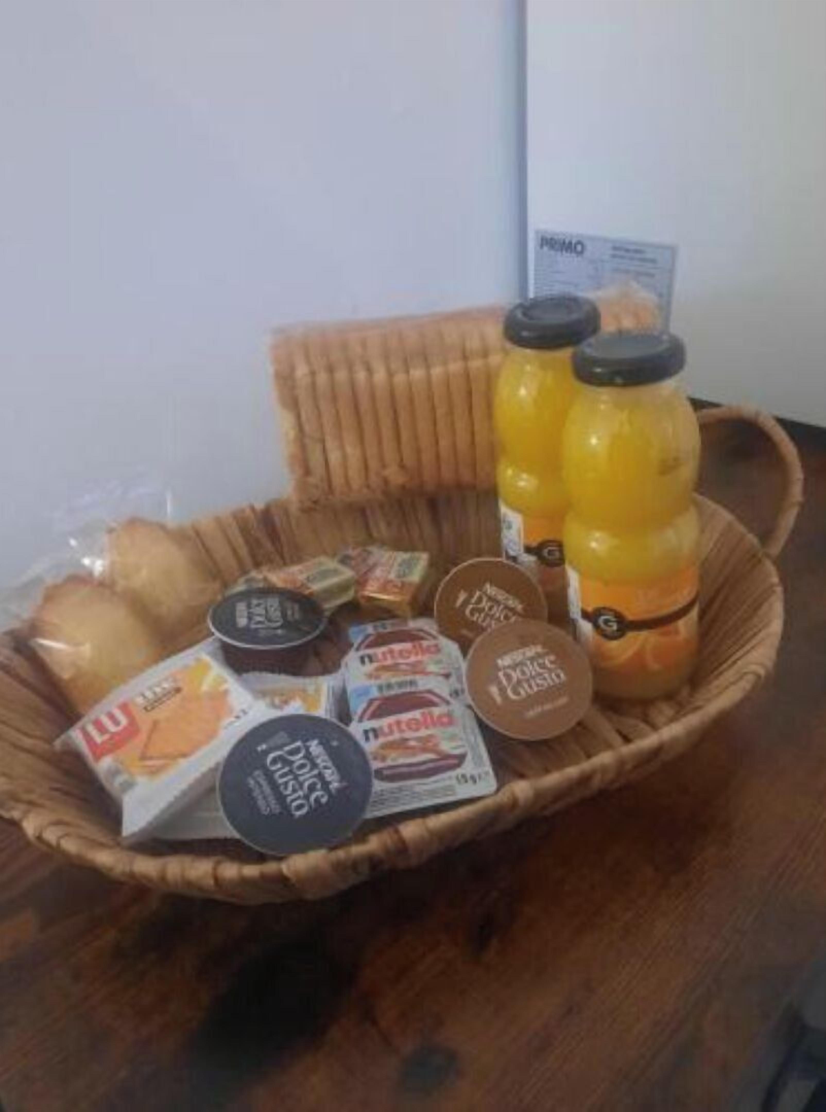 Una cesta con diversos alimentos y una botella de jugo.