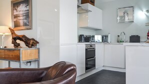 Een moderne keuken met witte kasten, een inbouwoven en een aanrecht met koffiezetapparaat en broodrooster.