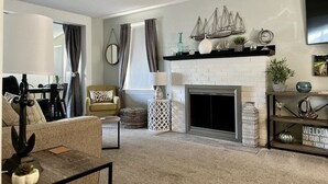 A living room with a fireplace, a sofa, a coffee table, and a TV mounted on the wall. - Lakeview Ashtabula, OH - 5 min to GOTL - Deck - King - Wineries - Lake Erie  (Ashtabula)