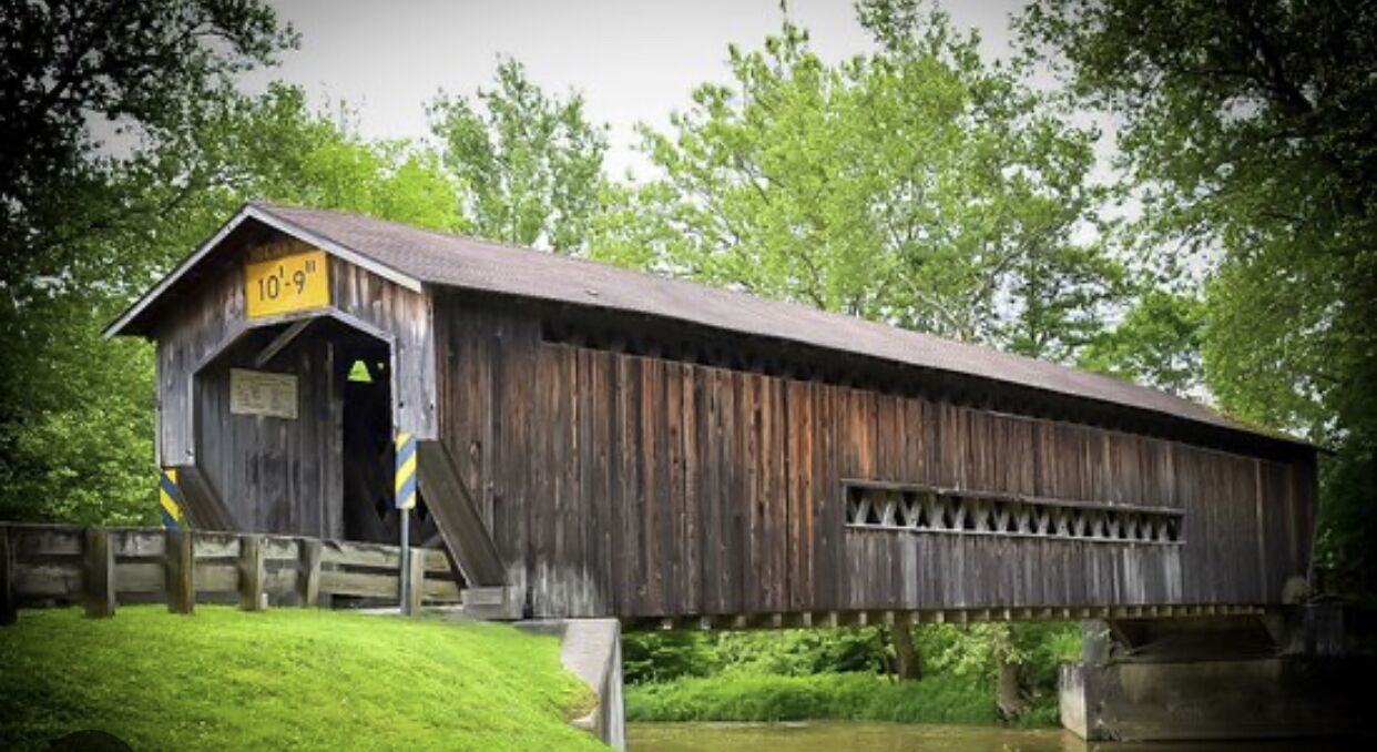 Eine hölzerne Brücke mit Vordach, an der eine Höhenbeschränkung von 3 Meter 30 Zentimetern angegeben ist.