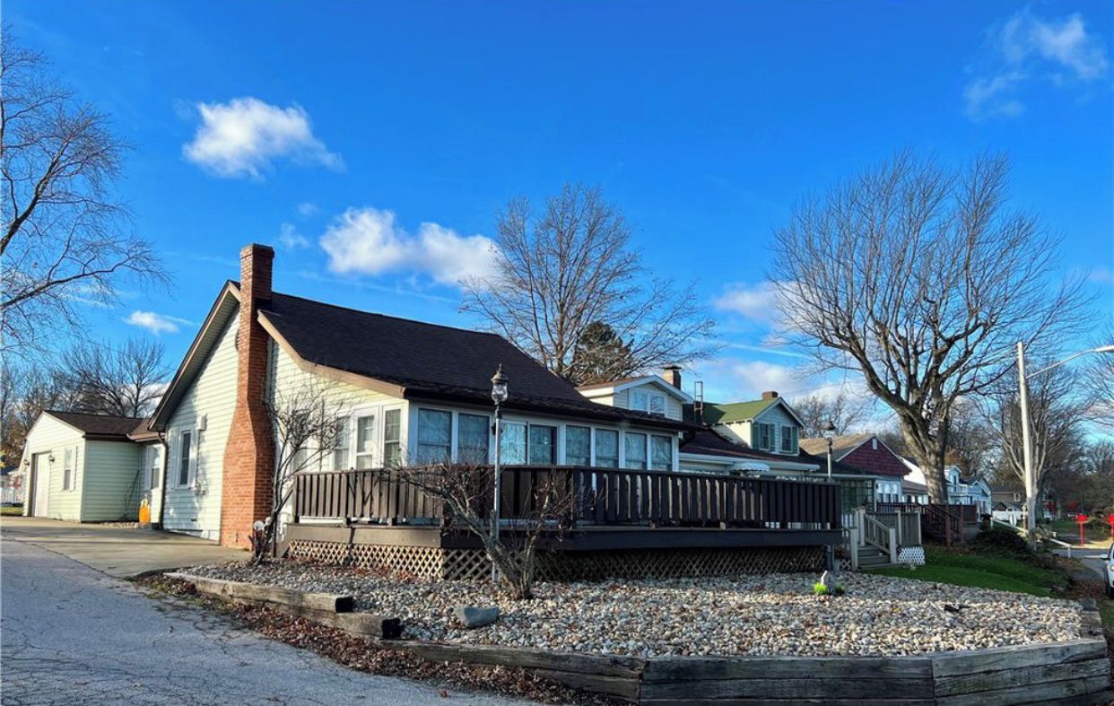 A two-story house with a brick chimney, a covered porch, and a small garden area.