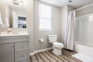 Un baño con inodoro, lavamanos, espejo y cortina de ducha.