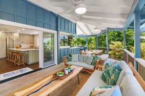 A modern kitchen with wooden cabinets and a dining area with a large window overlooking greenery. - Hoaloha- Few Steps to Hanalei Bay+AC & Hot Tub (Hanalei)