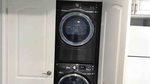 A compact laundry room with two stacked front-loading washing machines. - Beautiful One bedroom basement apartment (Toronto)