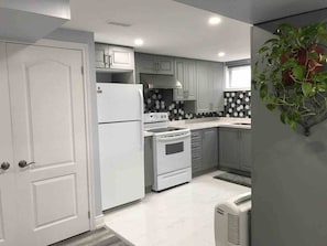 A modern kitchen with white cabinetry, a built-in oven, and a refrigerator.