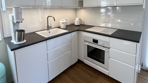 A modern kitchen with white cabinets, a black countertop, and a built-in oven. - Modern vacation apartment with feel-good terrace in Beerfelden (Oberzent)