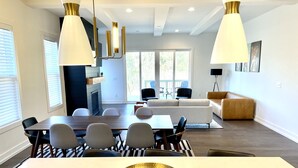 Ein modernes Wohnzimmer mit Essbereich, mit einem großen weißen Tisch, einer goldenen Schüssel und zeitgenössischen Möbeln.