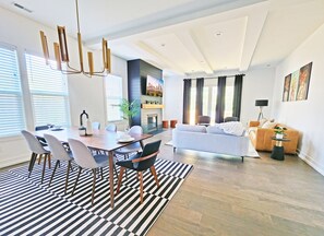 Een moderne woonkamer met een bank, een eettafel met stoelen, een televisie en een open haard.