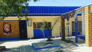 A building with a blue roof, a lion mural, and a small garden area with plants and a water feature.