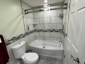A bathroom with a toilet, bathtub, and shower enclosure. - Cottage on Strip w/ 3 BDs 2 BAs (Geneva)