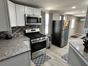 A modern kitchen with white cabinets, a stainless steel stove, a microwave, and a refrigerator.