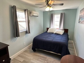 A bedroom with a bed, a ceiling fan, an air conditioning unit, and a window with curtains. - Cottage on Strip w/ 3 BDs 2 BAs (Geneva)