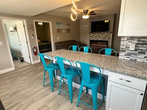 Eine Küche mit einer Granit-Arbeitsplatte, türkisfarbenen Stühlen, einem weißen Schrank und einem Kamin.