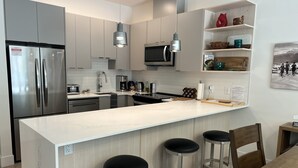 A modern kitchen with stainless steel appliances, a central island with stools, and a microwave above the island.