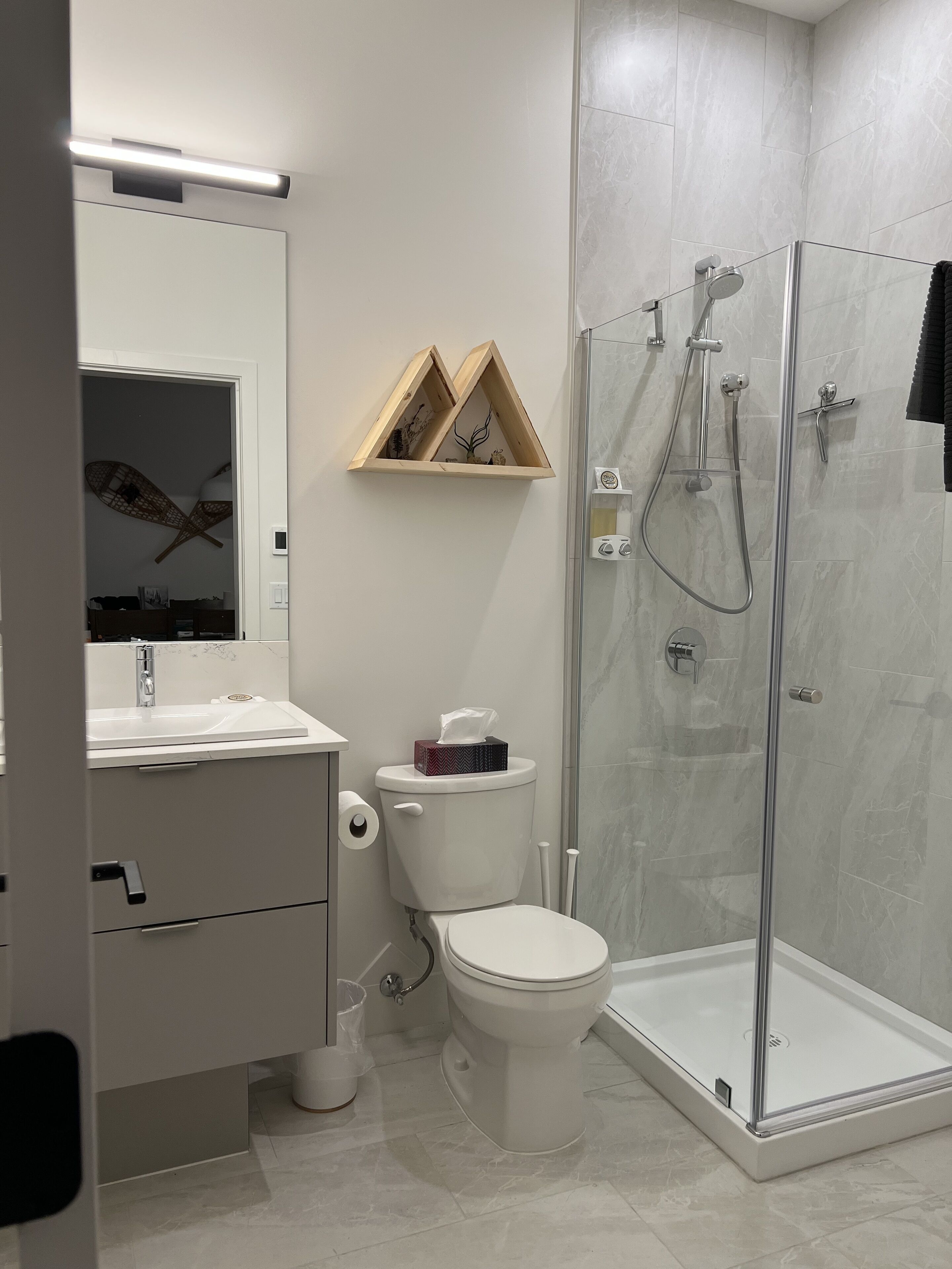 A modern bathroom with a toilet, sink, and glass-enclosed shower.