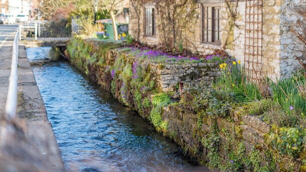 Un bâtiment en pierre, avec un étroit canal d’eau qui longe sa façade.