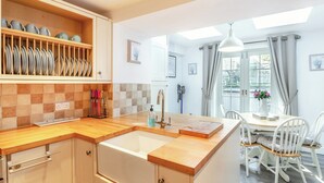Une cuisine dotée d’un plan de travail en bois, d’un évier et d’un coin repas avec une table et des chaises.