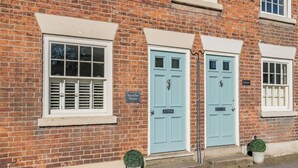 Un bâtiment en briques avec deux portes bleu clair, une enseigne indiquant « Beverley House », et une petite plante en pot placée de chaque côté d’une porte.