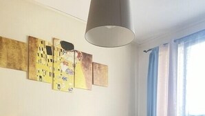 Ein Schlafzimmer mit einem großen Bett, einem Nachttisch mit Lampe und einem Kunstwerk an der Wand.