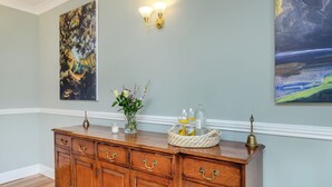 A wooden cabinet with drawers, a vase with flowers, and a tray with glasses and a bottle. - 6 bedroom accommodation in Beauly, near Inverness (Beauly, near Inverness)