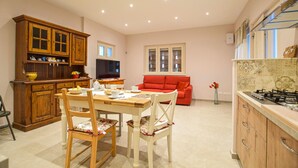 A kitchen with wooden cabinets, a dining table with chairs, a red sofa, and a TV. - 2 bedroom stunning home in Camaiore (Camaiore)