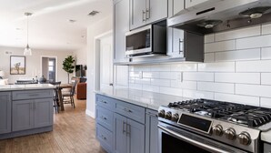Una cocina moderna con gabinetes grises, una estufa de acero inoxidable y un microondas.