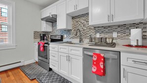 Une cuisine moderne avec des meubles blancs, un pare-feu en carrelage et des appareils électroménagers en acier inoxydable.
