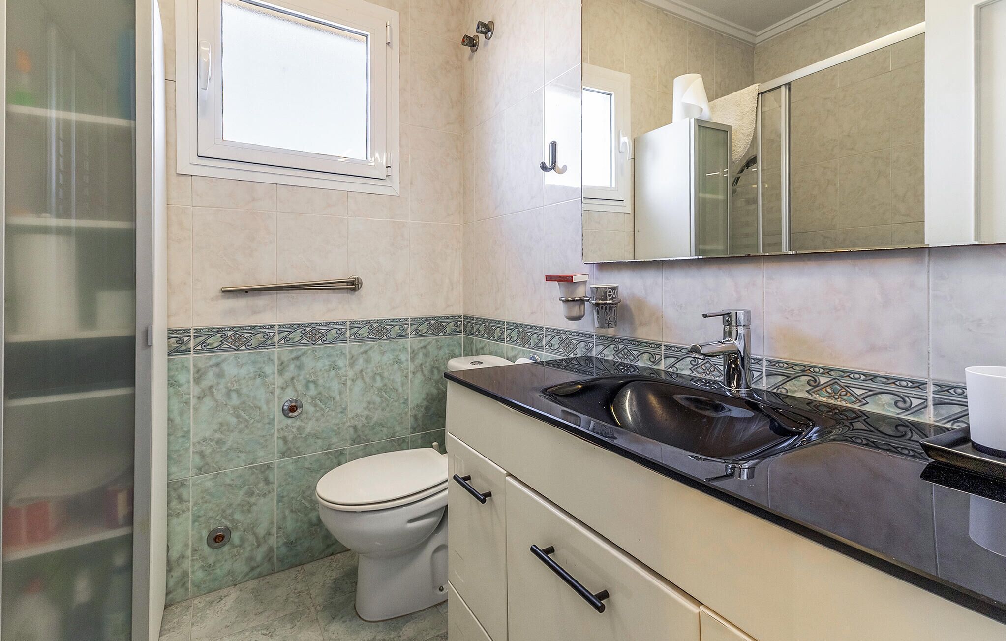 A bathroom with a toilet, sink, and mirror.