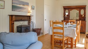 A cozy living room with a blue sofa, a fireplace, and a dining area with wooden chairs and a table set for four. - 3 bedroom accommodation in Rockcliffe, near Dalbeattie (Rockcliffe, near Dalbeattie)