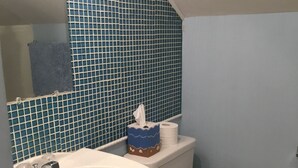 A bathroom with a white sink, toilet, and blue-tiled wall. - Nautical theme retreat located in the Ivory Mansion  (L'Anse)