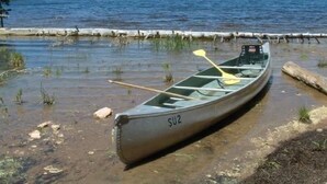 A canoe with a paddle on a rocky shore by a lake. - Off the grid cabin on private land surrounded by national forest. (Laramie)