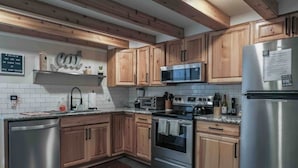 Une cuisine moderne avec des meubles en bois, des appareils électroménagers en acier inoxydable et un four à micro-ondes encastré.
