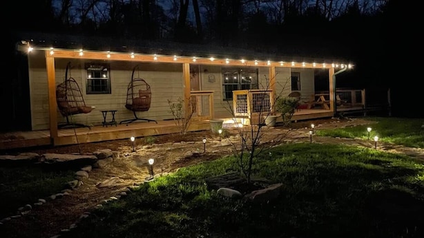 Une maison avec un porche, des sièges d’extérieur et des guirlandes lumineuses.
