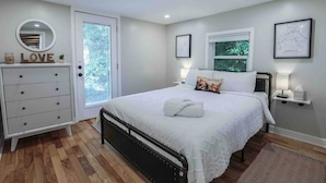 Une chambre à coucher comprenant un lit, une commode et une porte donnant sur un balcon.