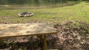 Una mesa de picnic en un área boscosa con un lago.