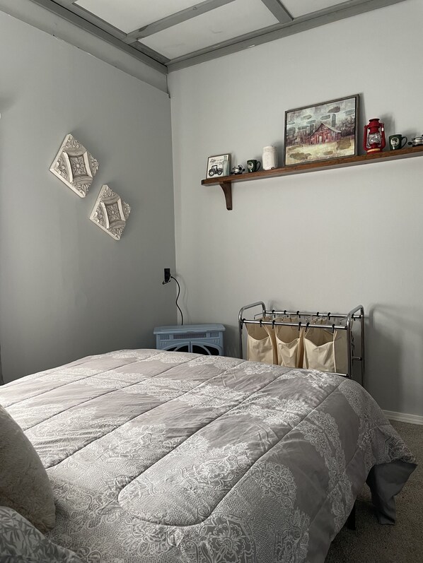 A bedroom with a bed, a shelf with decorative items, and a wall-mounted radiator.
